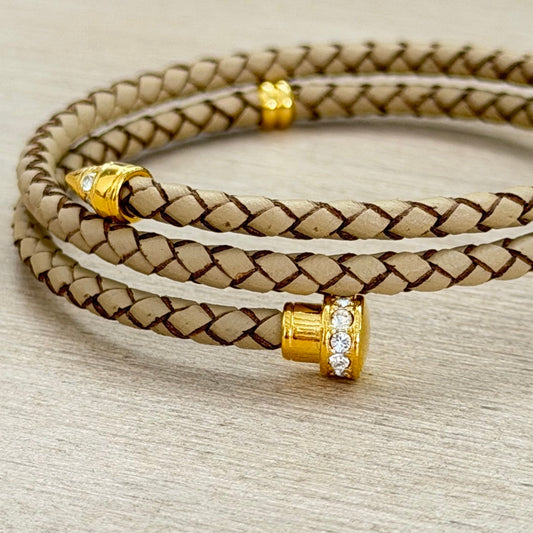 Beige braided leather bracelet with gold beads on a beige background